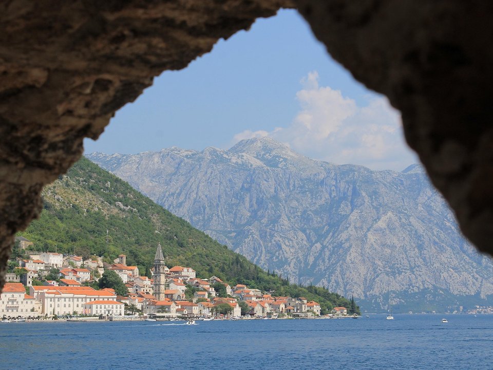 Perast and the mountains of Boka Bay seen through a stone arch