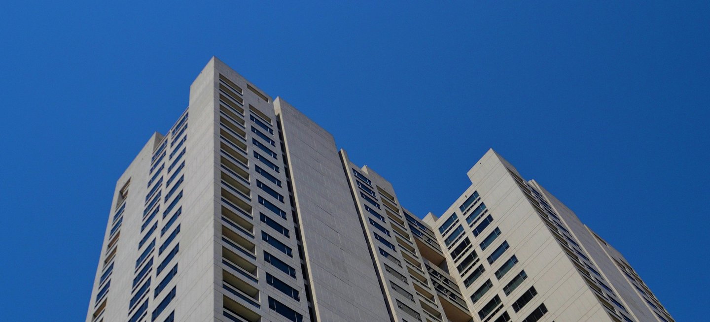 A residential tower managed by Levimax, seen from below against a clear sky